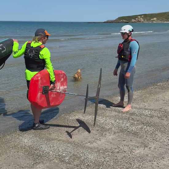 Surf to summer instructor demonstrating beach access whilst carrying equipment hard to Foil Wing  North Wales crystal clear Kite Foil and tow Foil conditions